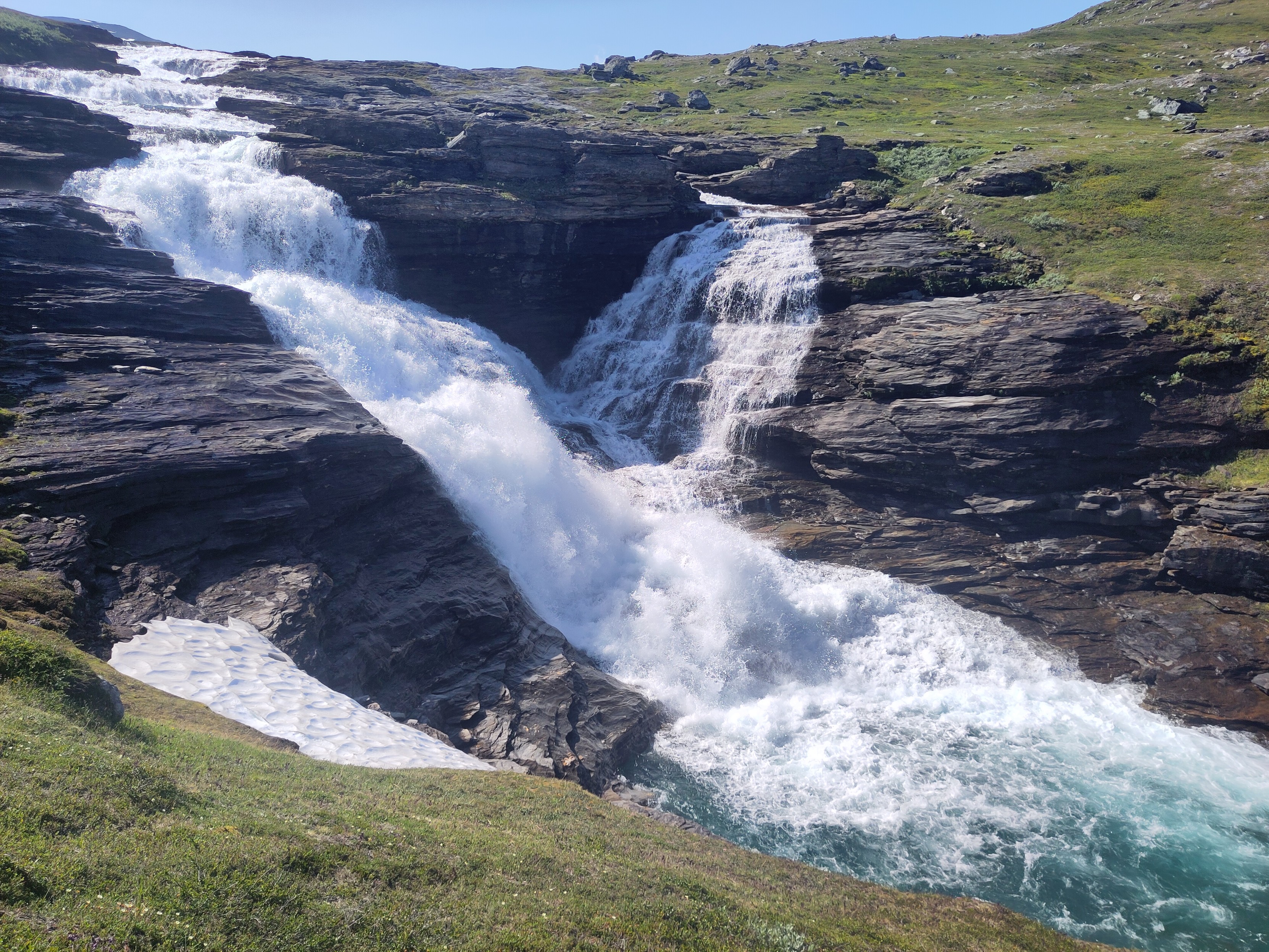 A waterfall going down the rock shelves in sunlight