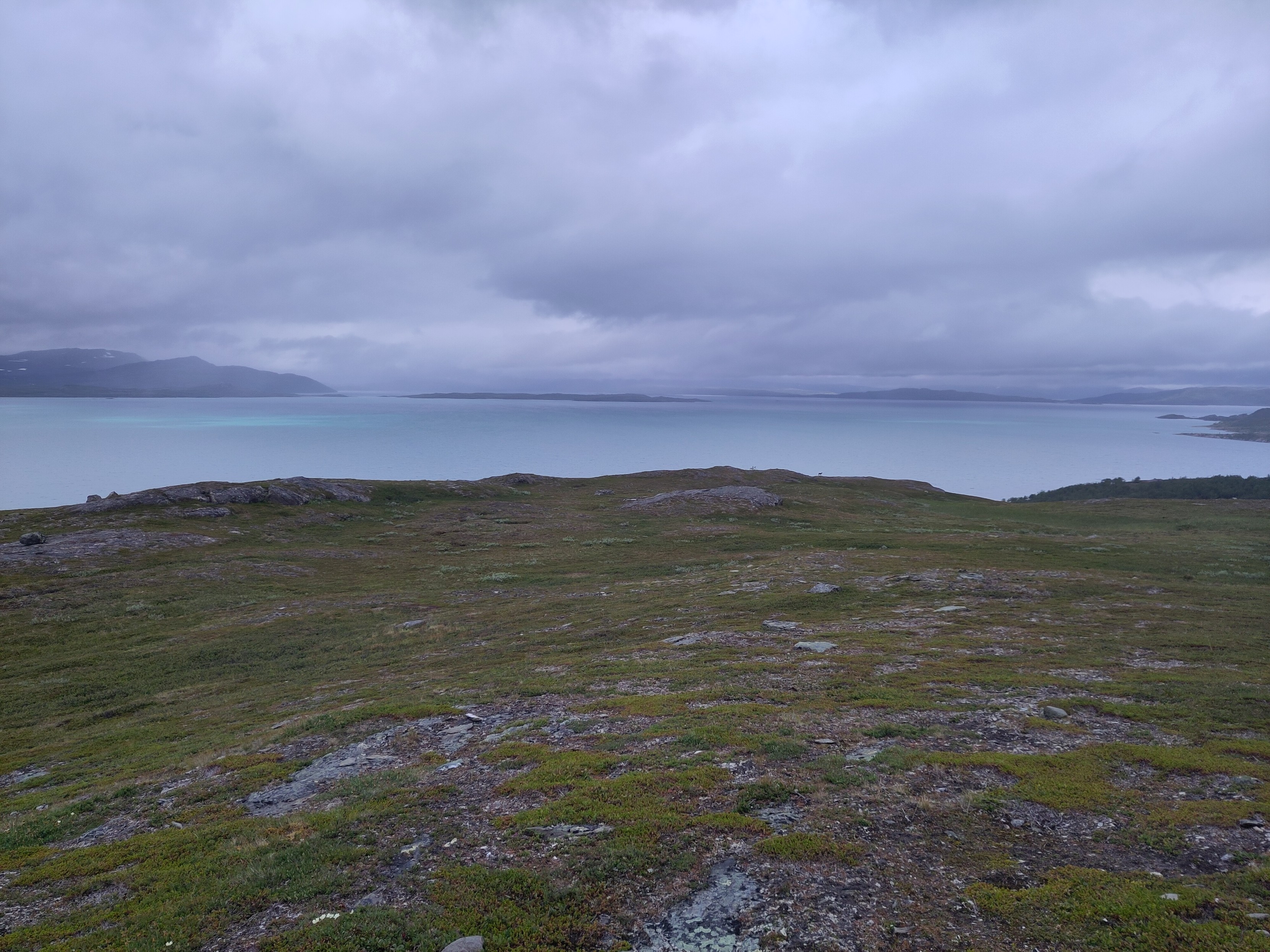 A large lake from above, with low clouds. A big island can be seen in the distance.