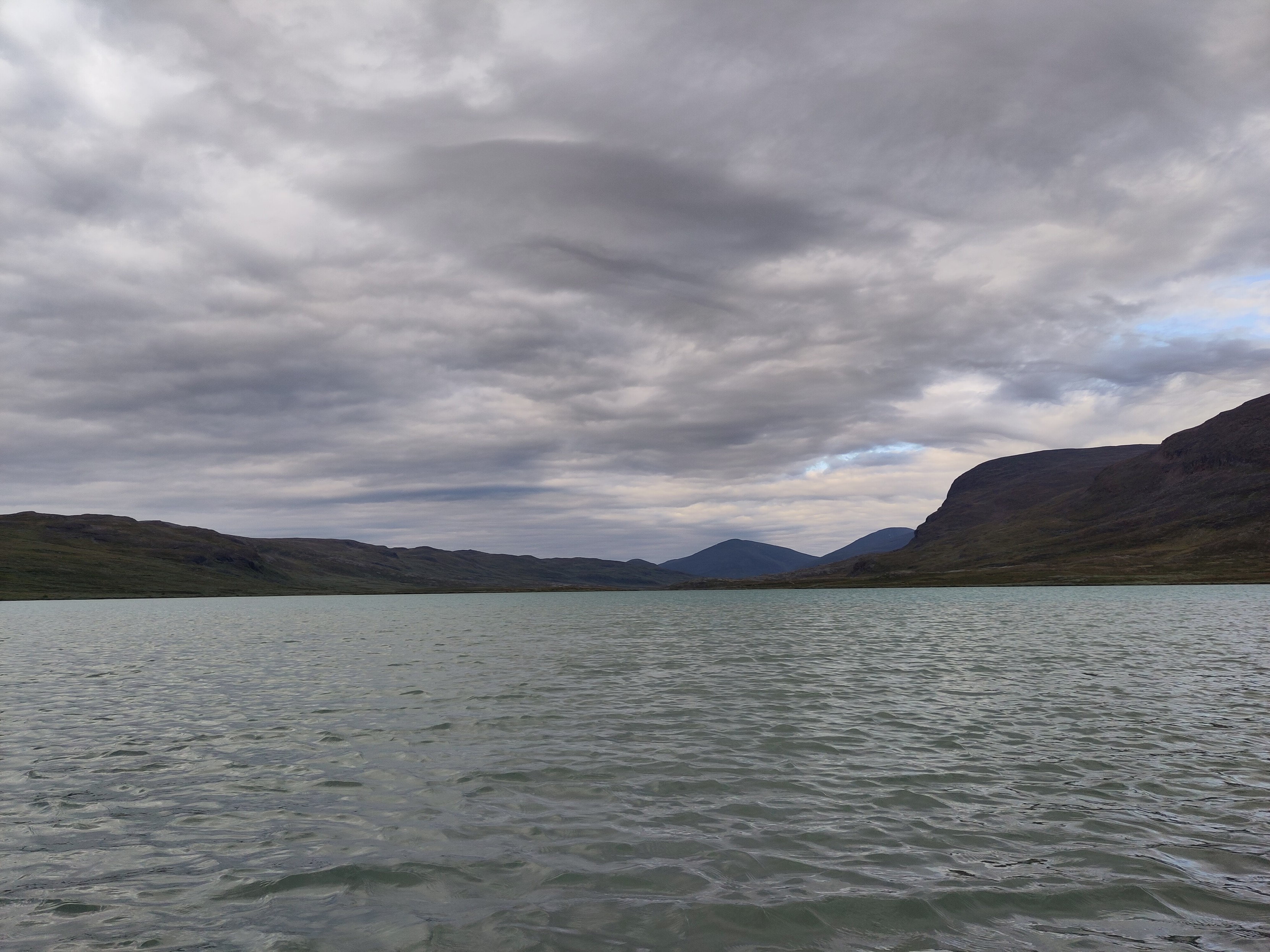 The grey-green Alisjárvi lake under a cloudy sky.